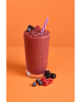 Berry smoothie mix with some berries and straw on an orange and white background