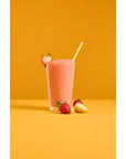 Glass cup of a Davinci fruit smoothie mix with strawberries and bananas on an orange and white background