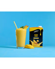 Glass cup with fruit smoothie with mango slices and straw next to Davinci Mango Mania smoothie mix on a blue and white background