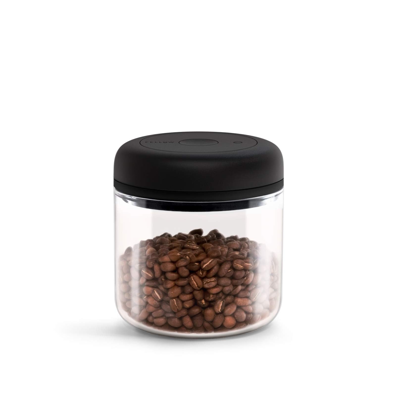 Glass jar with black lid filled with coffee beans on a white background