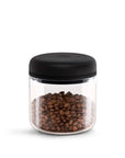 Glass jar with black lid filled with coffee beans on a white background