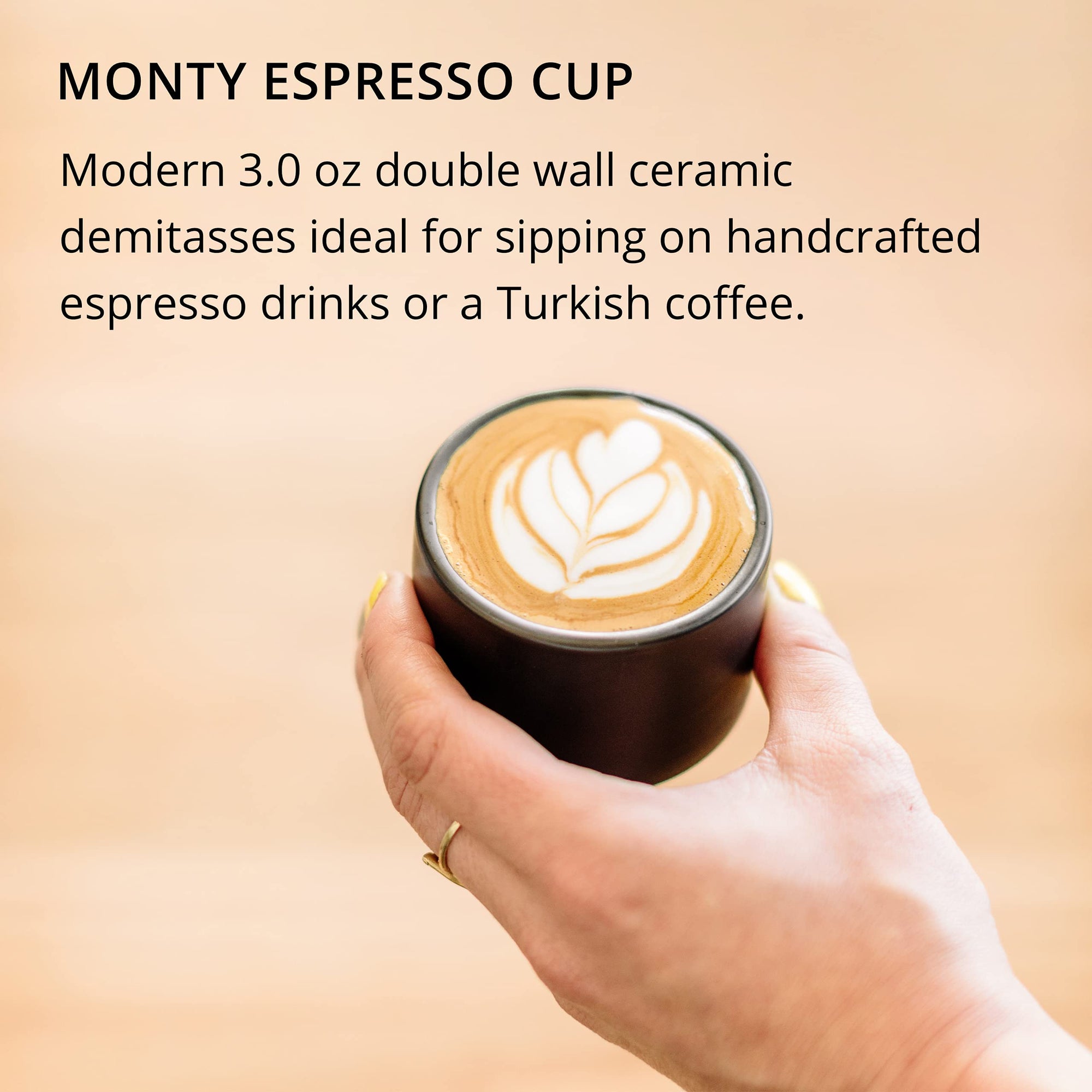Hand holding a Monty Espresso Cup with a latte art design on a beige background with text about Monty Espresso Cup