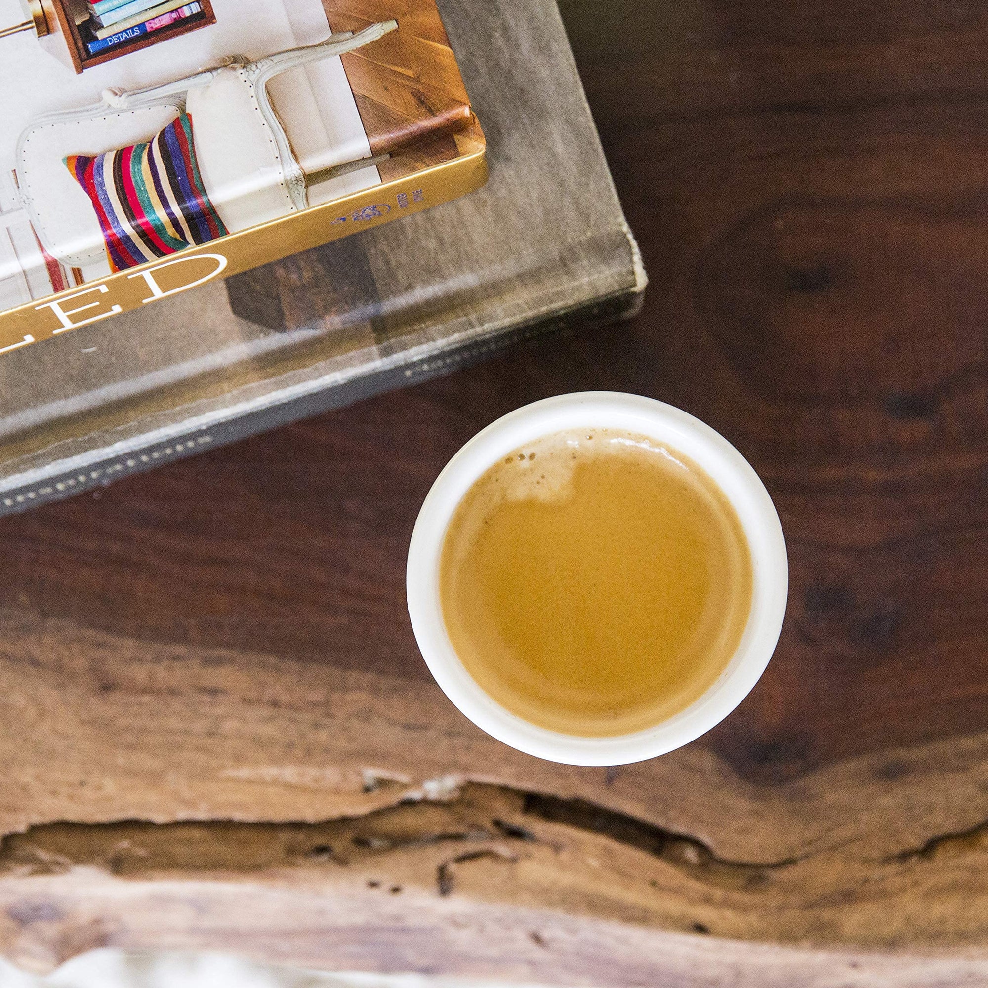 Cup of coffee on a wooden surface with a book in the background