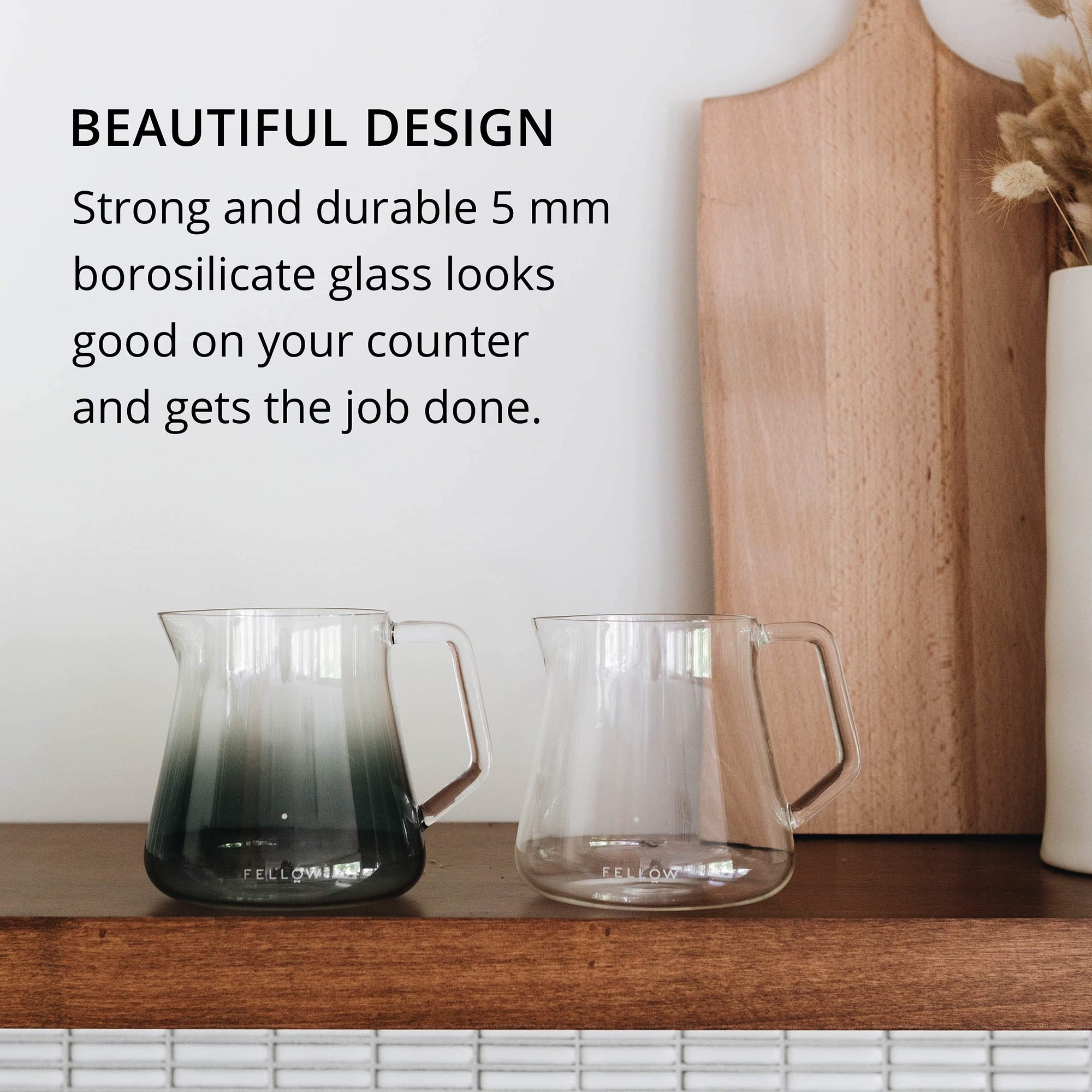 Two glass pitchers on a wooden surface with text about borosilicate glass.
