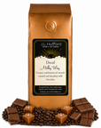 1 lb J.L. Hufford Decaf Milky Way coffee bag with coffee beans, chocolate, and blocks of caramel on a white background