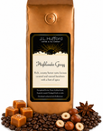 1 lb J.L. Hufford Highlander Grogg coffee bag with coffee beans, blocks of caramel, hazelnuts, and spice on a white background