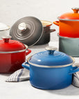 A set of Le Creuset Enamel on Steel Traditional Petite Stockpots in various colors including red, blue, green, and gray.