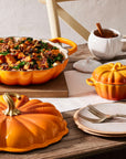 Table setting with pumpkin-themed dishes and a bowl of salad.