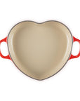 Top view of cerise heart shaped 1.25 qt cocotte with handles displayed on a white background