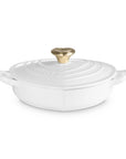 Side view of white heart shaped 1.25 qt cocotte with handles and a light gold heart knob displayed on a white background