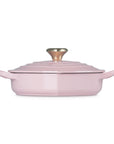Side view of chiffon pink heart shaped 1.25 qt cocotte with handles and a light gold heart knob displayed on a white background