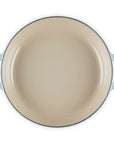 Beige enamel pan with blue handles on a white background