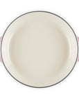 Round enamel pan with pink handles on a white background