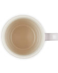 White mug with a small amount of brown liquid on a white background