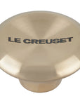 Light gold knob with 'Le Creuset' branding on a white background