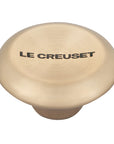 Light gold knob with 'Le Creuset' branding on a white background