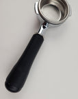 Coffee scoop with black handle and metal basket on a light gray background
