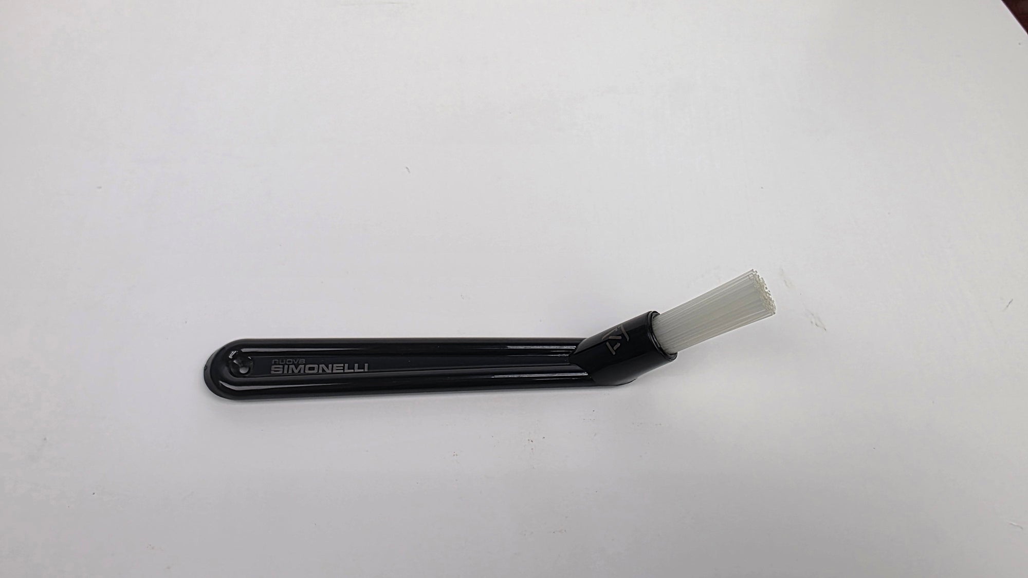Black plastic tool with a white brush on a white background