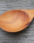 Close up of spoon of Rico & Plato almira teak spoon on a wooden surface