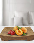 Rico & Plato mick teak serving tray with strawberries and peaches on the serving tray displayed on a white countertop in a living room setting