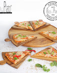 A teak wood pizza serving board with segmented slices and a slimline base, displayed with pizza slices on it on a white background