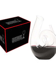 Riedel curly handmade decanter with red wine inside next to packaging displayed on a white background
