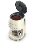 Top view of cream Smeg coffee machine with top open with a view of grounded coffee beans on a white background