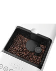 Top view of a white Smeg fully automatic coffee machine showing where the coffee beans are contained on a white background