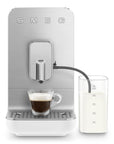 White, silver Smeg fully automatic coffee machine with auto milk froth to the side and with a creamy espresso shot on a white background
