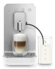 White, silver Smeg fully automatic coffee machine with auto milk froth to the side and with a creamy coffee on a white background