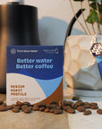 Third Wave Water packaging with coffee beans on a wooden surface