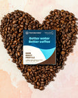 Heart-shaped arrangement of coffee beans with a Third Wave Water package on a light background