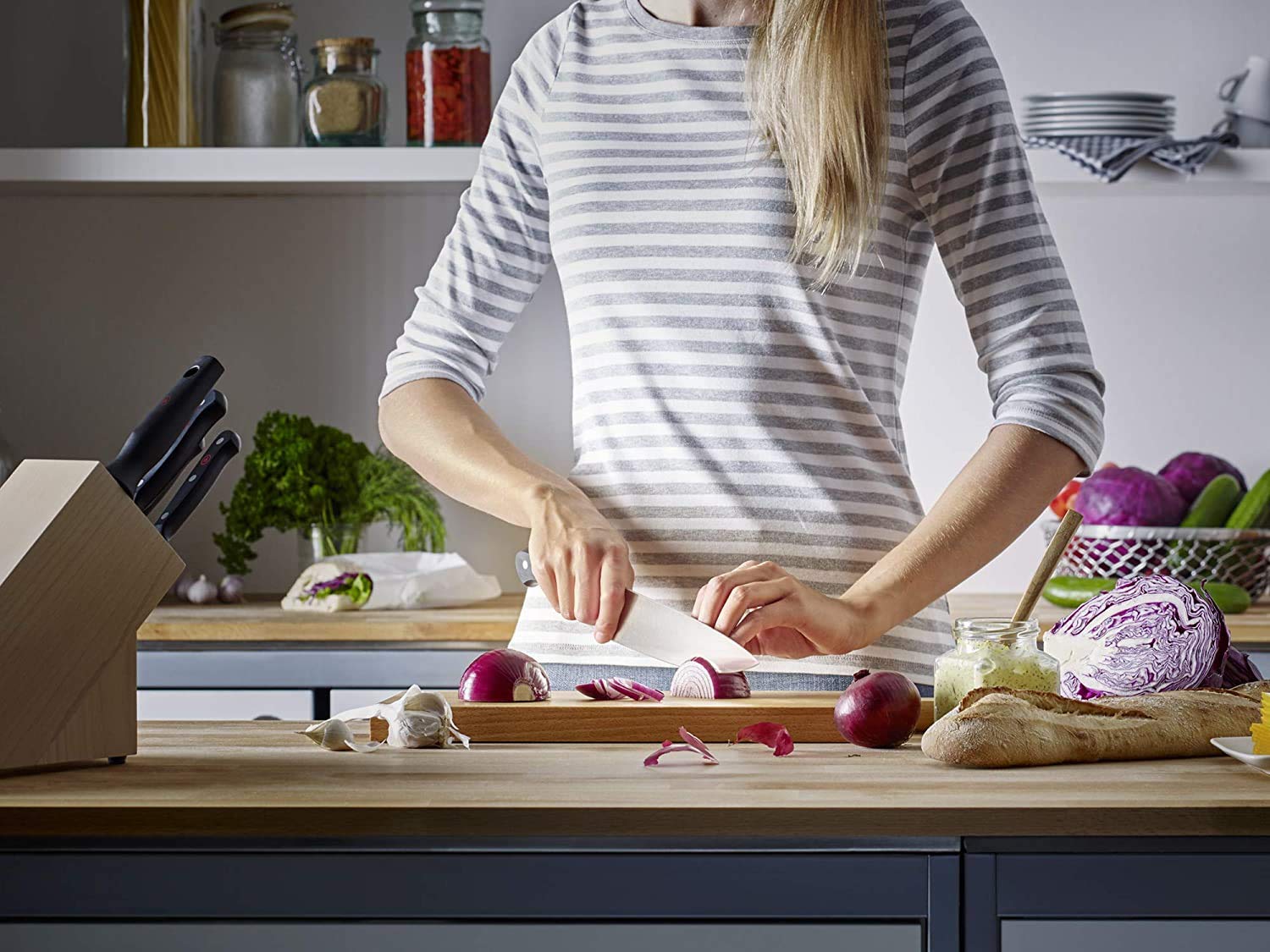 Person preparing food in a kitchen with various vegetables and utensils.