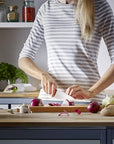 Person preparing food in a kitchen with various vegetables and utensils.