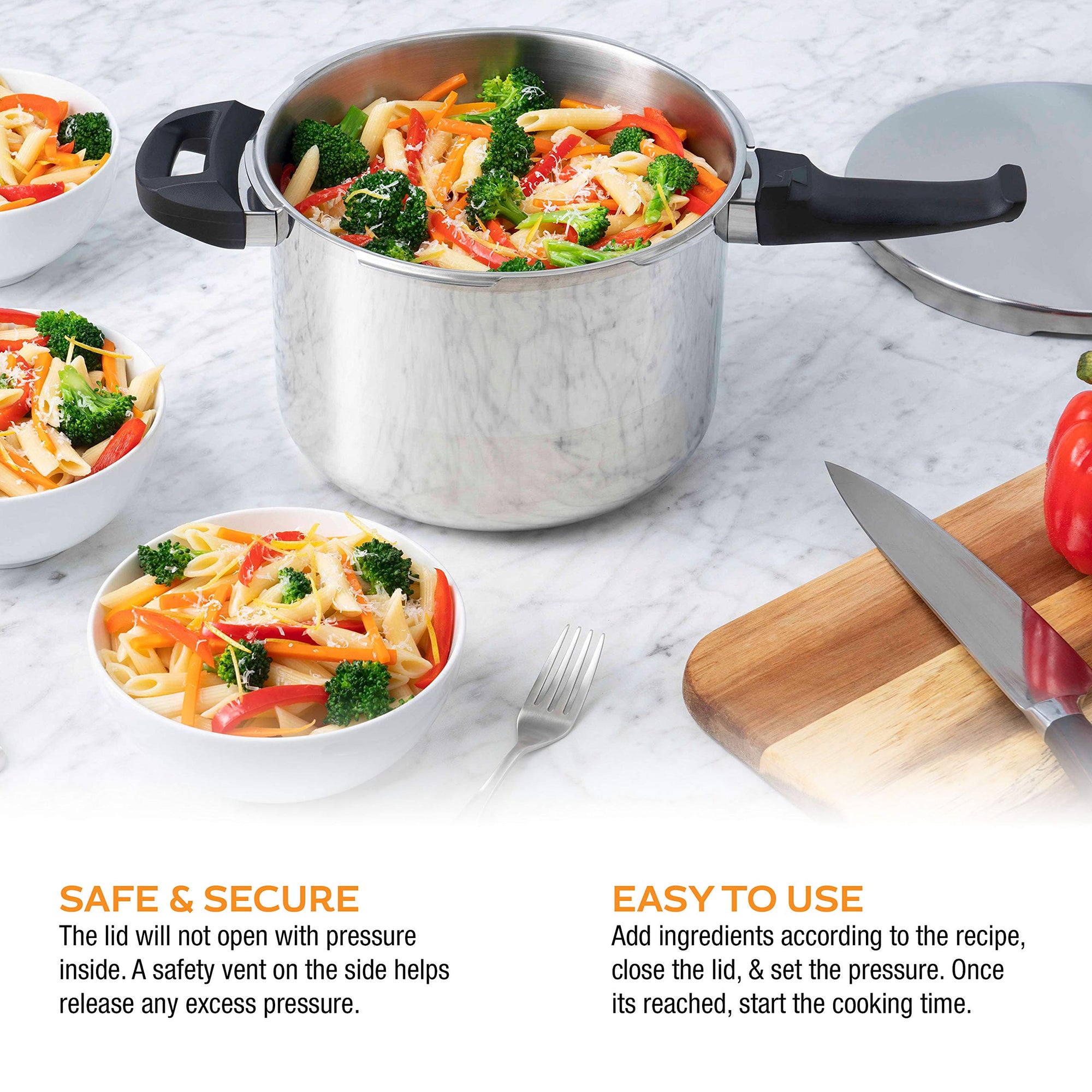 Stainless steel pressure cooker with vegetables on a marble countertop, surrounded by bowls of pasta and a cutting board with a knife.