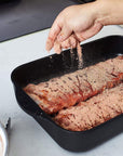 Swiss Diamond Roasting Pans 12.5" x 10" (4.8 Qt) Swiss Diamond XD Nonstick Roasting Pan with someone sprinkling spices on a meat in a kitchen setting