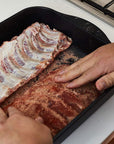 Swiss Diamond Roasting Pans 12.5" x 10" (4.8 Qt) Swiss Diamond XD Nonstick Roasting Pan with someone rubbing spices on uncooked meat