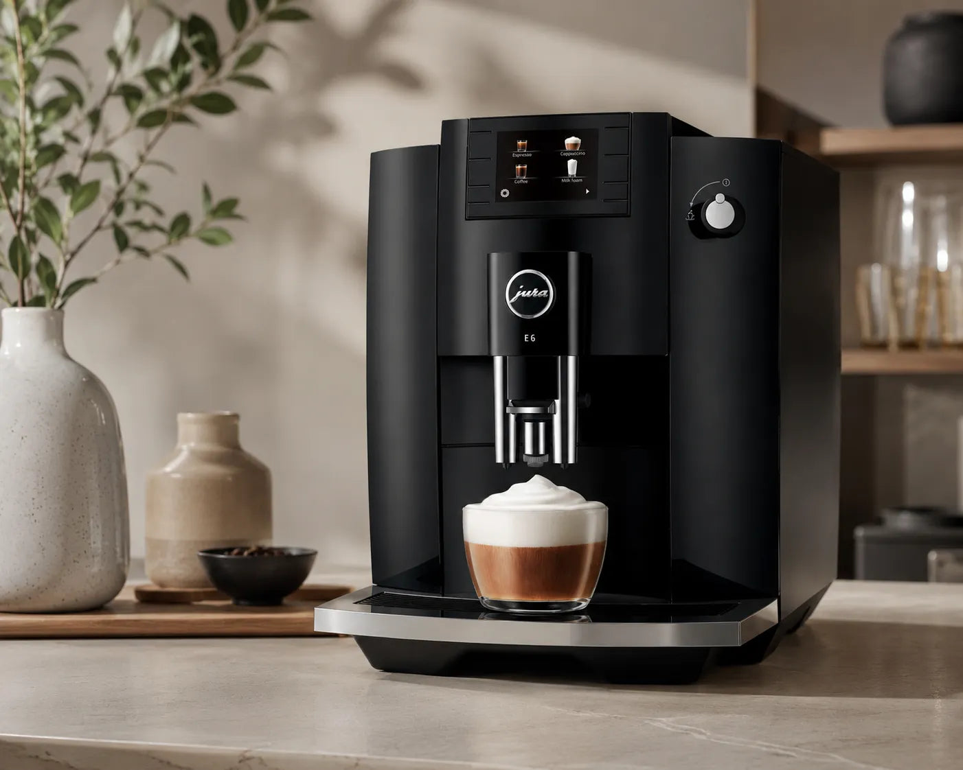 Black Jura coffee machine dispensing a cappuccino on a kitchen counter with decorative items in the background.