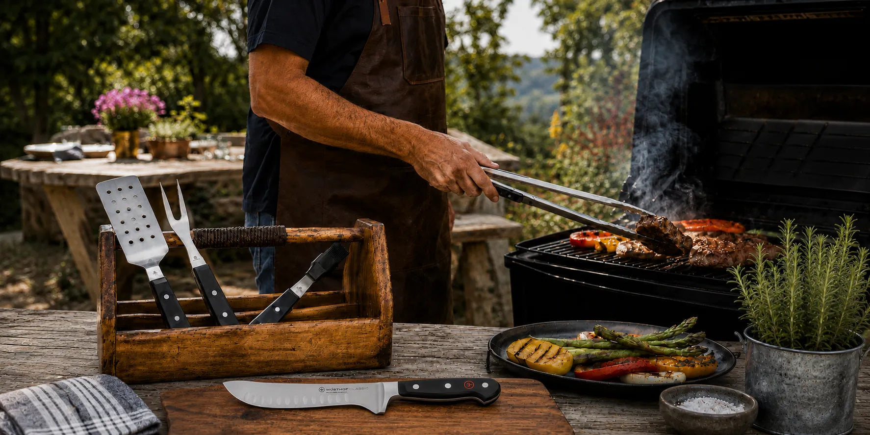 Person grilling outdoors with a wooden utensil holder and tools on a table.