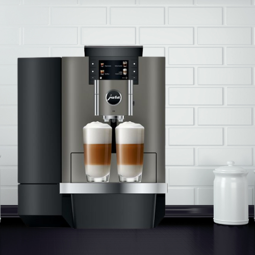 Modern coffee machine with two glasses of coffee on a white tiled wall background