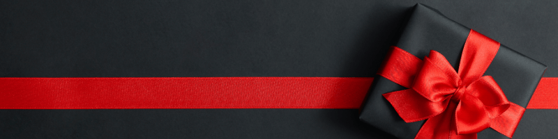 Black gift box with a red ribbon and bow on a black background featuring Black Friday Deals.