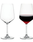 Two clear stemmed wine glasses on a white background, with the left glass empty and the right glass partially filled with red wine.