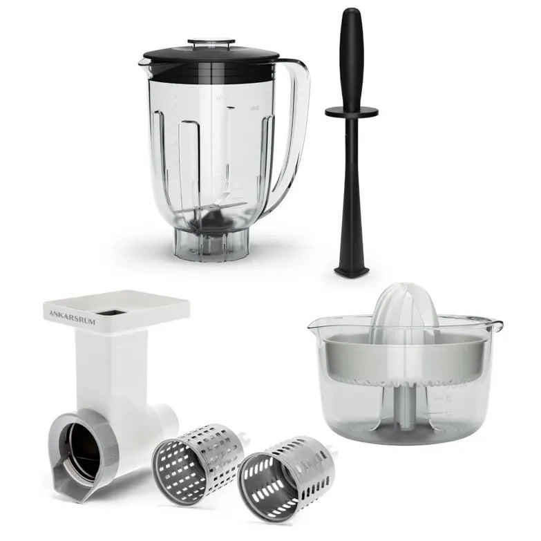 A kitchen blender parts set on a white background, including a clear blender jar with a black lid, a black muddler, a white and clear juicer, and two stainless steel shredding/cutting attachments.