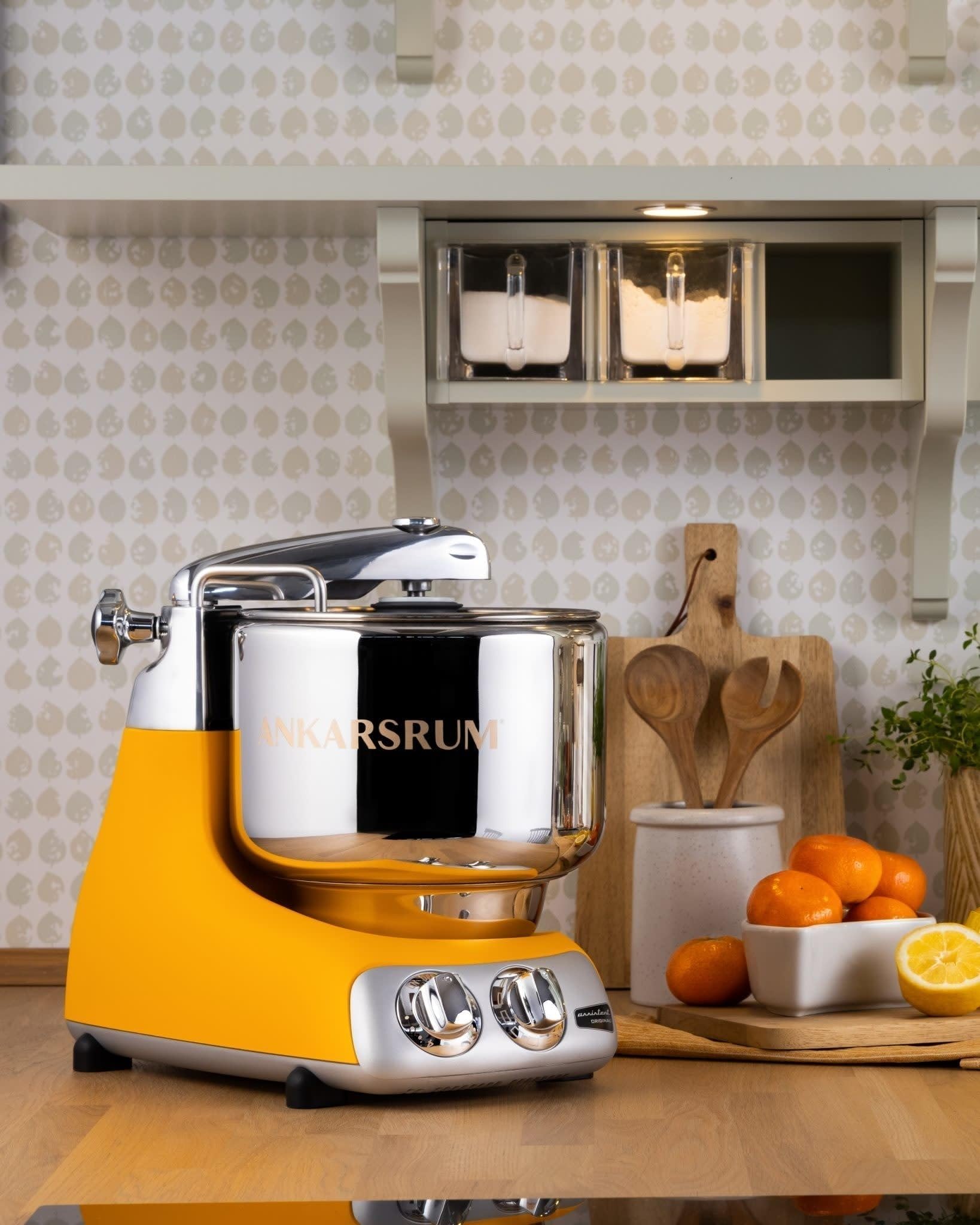 Yellow kitchen stand mixer on a countertop with a kitchen setting in the background