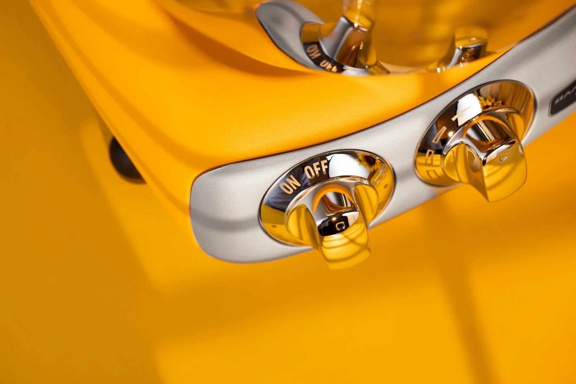 Close-up of a yellow appliance with metallic control panel on a yellow background