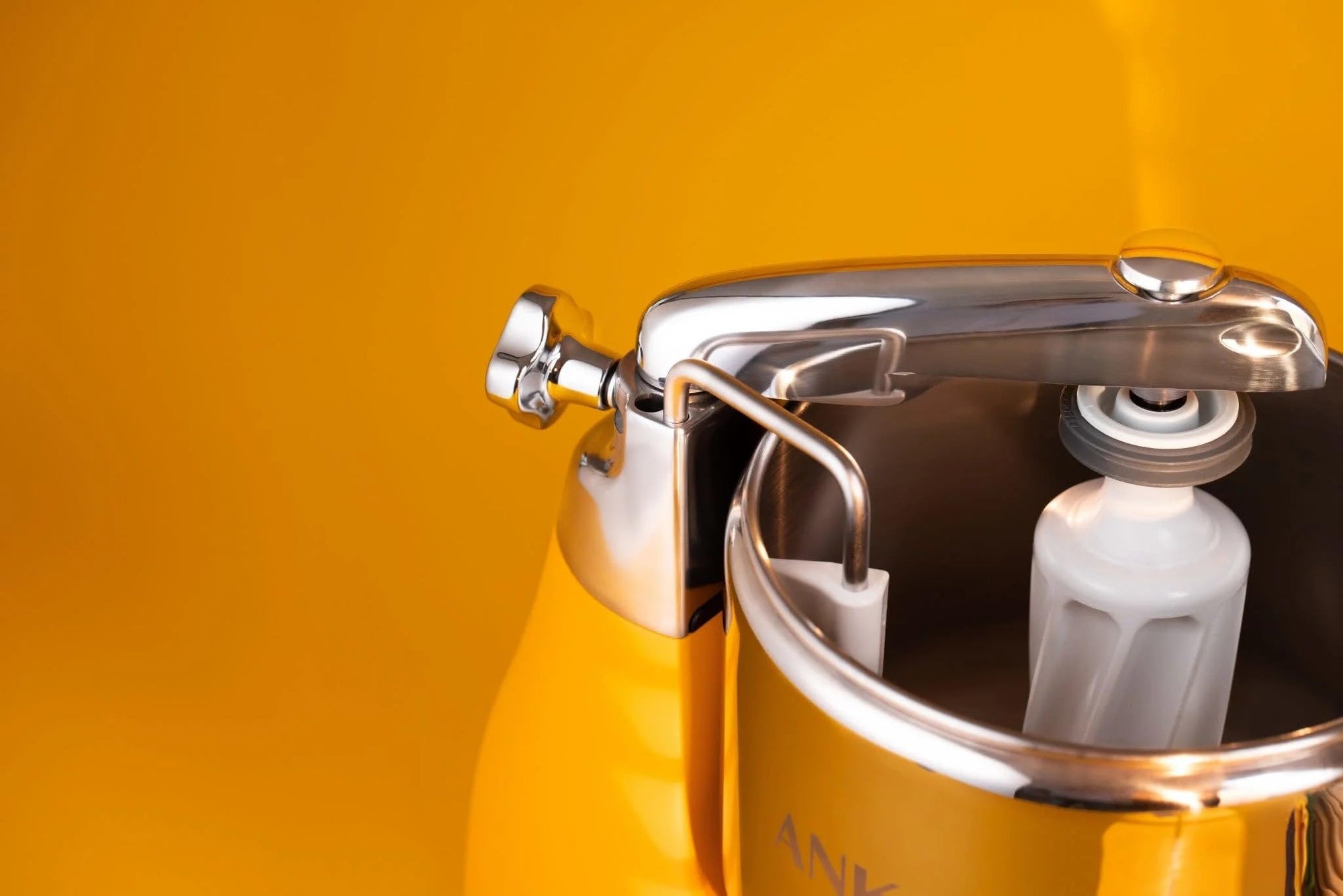 Close-up of a metallic container with a white bulb inside against a yellow background