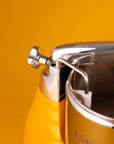 Close-up of a metallic container with a white bulb inside against a yellow background