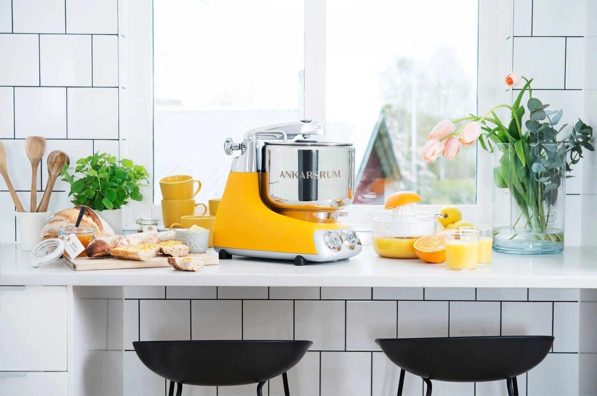 Yellow kitchen stand mixer on a white countertop with a tiled wall background