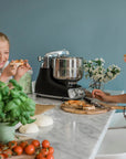 Two young girls in a kitchen preparing food with a stand mixer.