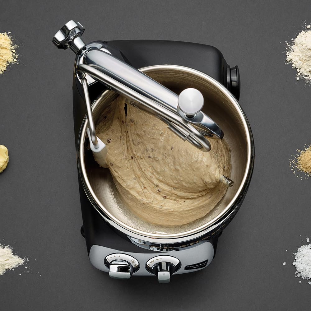 Kitchen mixer with dough in mixer with attachment on a dark background